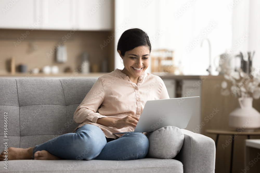 Indian woman resting on sofa spends leisure on internet, chatting with friend, scroll news feed, read post, watching on-line movies through subscription-based streaming online services using laptop Indian woman resting on sofa spends leisure on internet, chatting with friend, scroll news feed, read post, watching on-line movies through subscription-based streaming online services using laptop