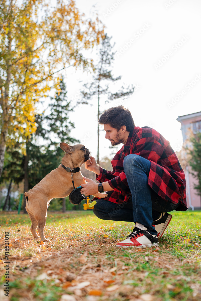A man is training his dog using treats in the park, building a bond on a pleasant autumn afternoon A man is training his dog using treats in the park, building a bond on a pleasant autumn afternoon