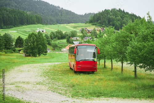 Red bus and village houses in picturesque green landscape