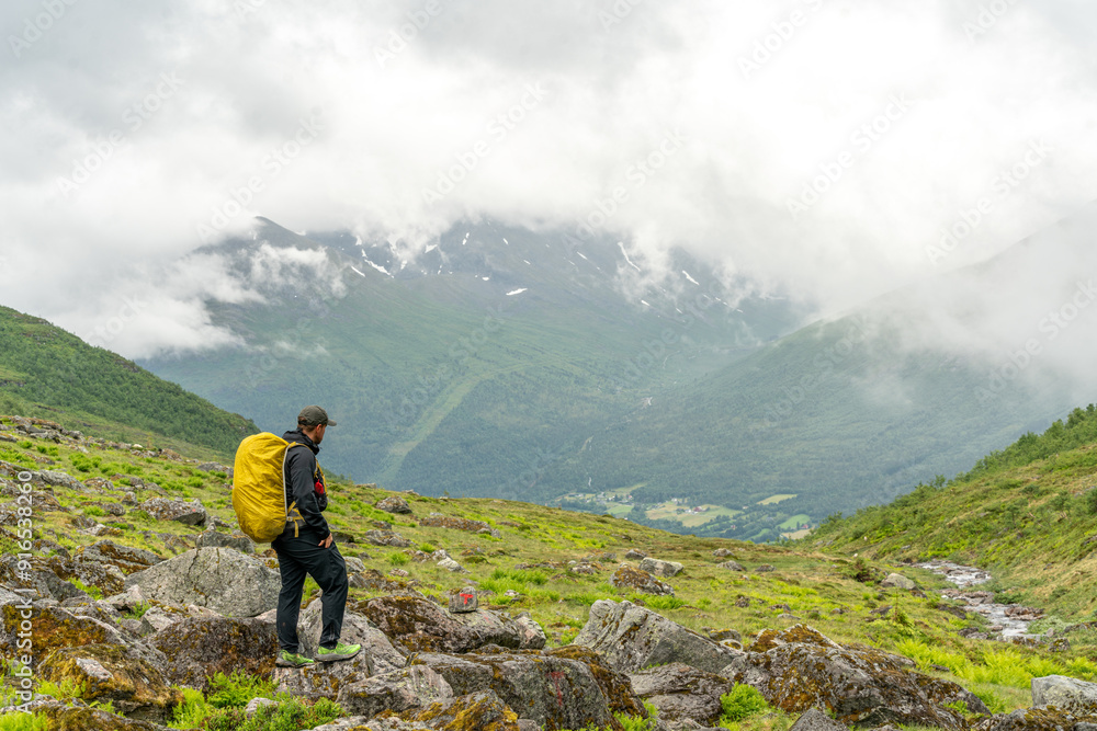 male photographer hiking in the fjord of isfjorden andalsnes in norway on a rainy day