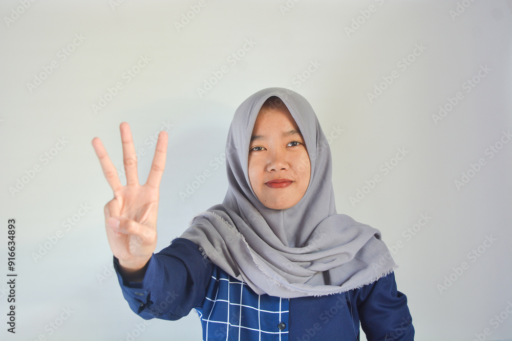 Young indonesian woman wearing hijab over isolated white background showing and pointing up with fingers number three while smiling confident and happy. Young indonesian woman wearing hijab over isolated white background showing and pointing up with fingers number three while smiling confident and happy.