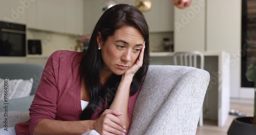 Upset young woman sits on sofa at home looks insulted and frustrated, having problems in relationships, thinks on divorce, suffers from break up, separation, marriage split. Nostalgic mood, solitude