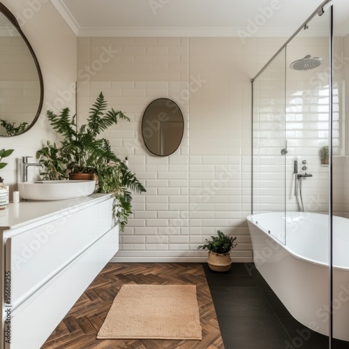 A bathroom with a white tile wall and a white sink. A plant is on the counter next to the sink