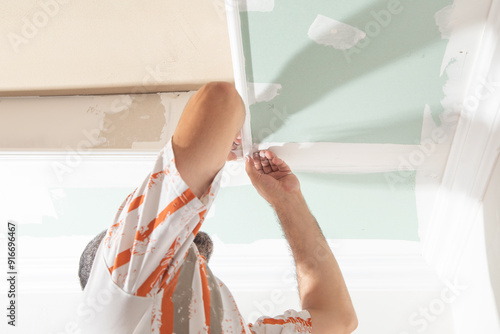 Caucasian worker renovating ceiling at home.