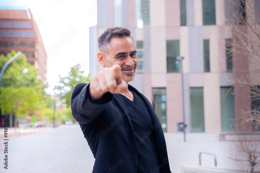 Confident middle adult pointing finger to front of logo. Smiling man pointing finger towards camera. Confident middle adult pointing finger to front of logo. Smiling man pointing finger towards camera.