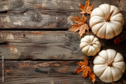 Autumn arrangement of white pumpkins and fallen leaves on rustic wooden surface, copy space for text