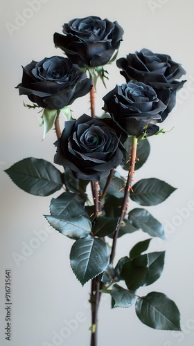 A bouquet of striking black roses with deep green leaves, arranged elegantly against a light background, showcasing unique beauty