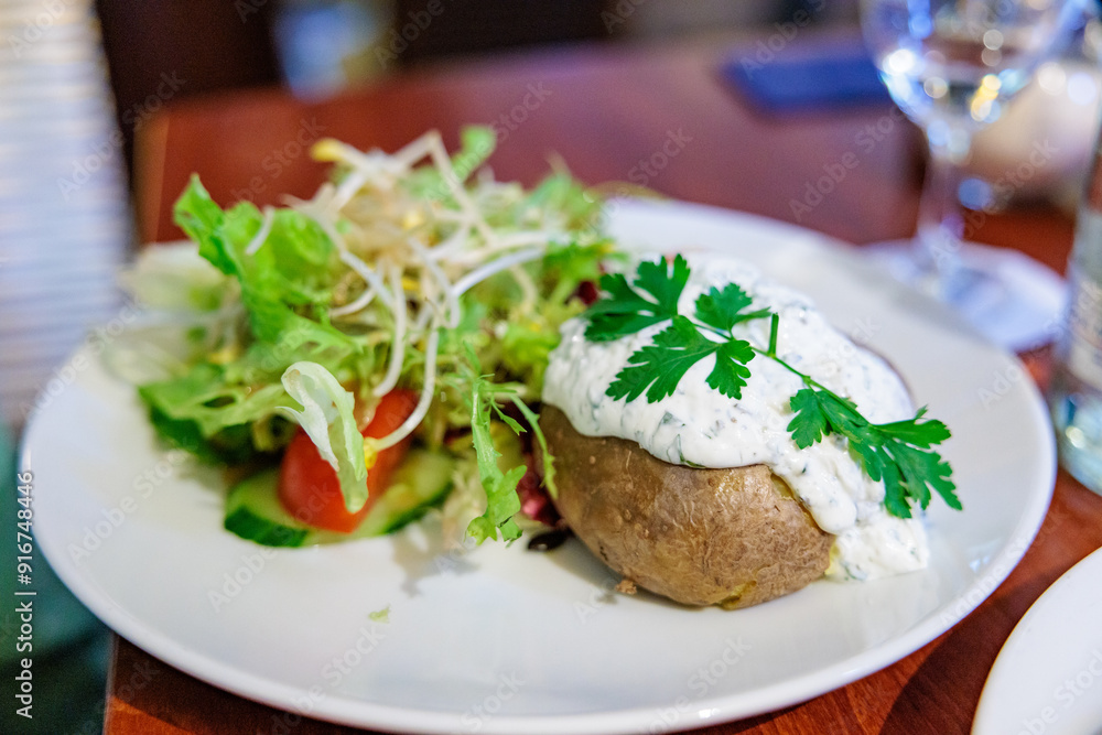 Baked Potato Topped with Crème Fraîche and Fresh Salad in a Restaurant Setting Baked Potato Topped with Crème Fraîche and Fresh Salad in a Restaurant Setting