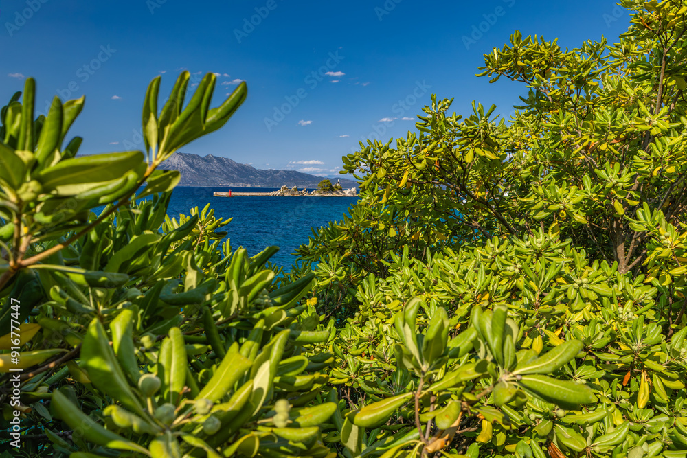 Obraz premium Port in Trpanj, Peljesac Peninsula in Croatia, view of the statue of the Virgin Mary, rough Adriatic sea