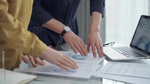 Business team analyzing financial charts on desk. Professionals discussing data at a workstation with laptops and documents. Audit and finance concept