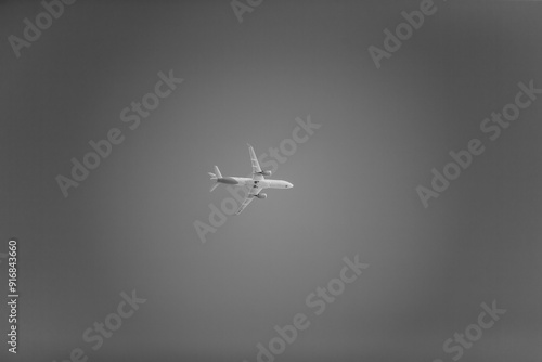 Black and white photo of plane flying in the sky very far away in high speed. passenger flight