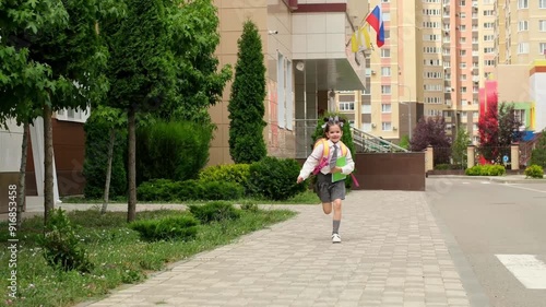 Wallpaper Mural back to school, a schoolgirl joyfully runs from school to her parents with a backpack and books in her hands, a child girl goes to the first grade, the first day of school Torontodigital.ca