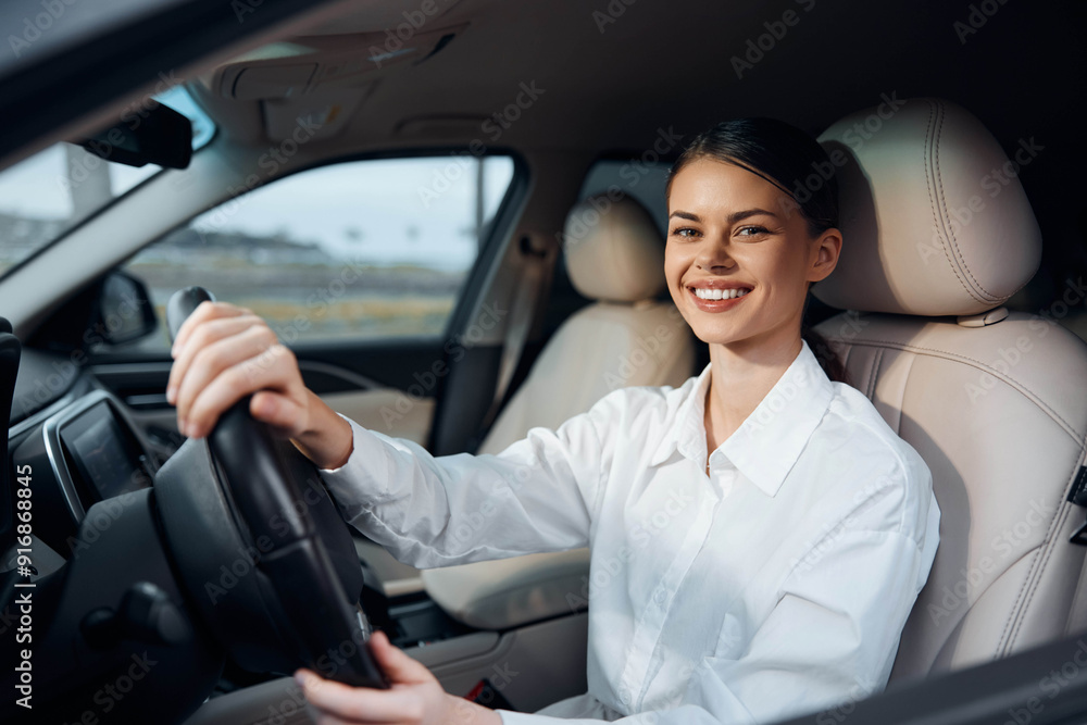 A cheerful woman is seated in the driver's seat of a car, holding the steering wheel and smiling brightly A cheerful woman is seated in the driver's seat of a car, holding the steering wheel and smiling brightly
