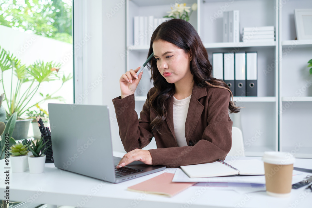 A young businesswoman is focused on her work while sitting at her home office desk. A young businesswoman is focused on her work while sitting at her home office desk.