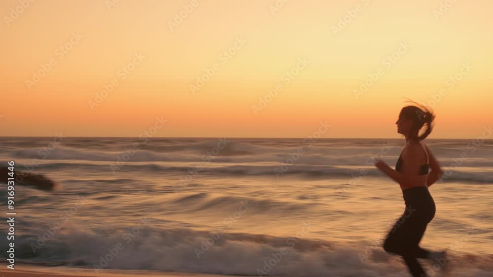 Determined female jogger running on seashore during sunset at beach. Excited sportswoman performing splits in midair at the end of her run on sandy coast. Determined female jogger running on seashore during sunset at beach. Excited sportswoman performing splits in midair at the end of her run on sandy coast.