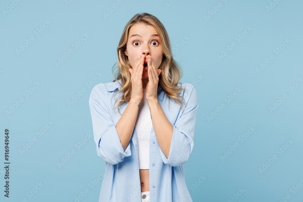 Young shocked surprised happy woman she wears white top shirt casual clothes cover mouth with hands look camera isolated on plain pastel light blue cyan background studio portrait. Lifestyle concept. Young shocked surprised happy woman she wears white top shirt casual clothes cover mouth with hands look camera isolated on plain pastel light blue cyan background studio portrait. Lifestyle concept.