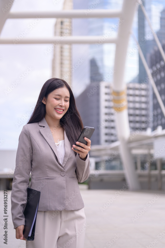 Young professional woman is walking outdoors in a modern urban environment, focused on her smartphone. Young professional woman is walking outdoors in a modern urban environment, focused on her smartphone.