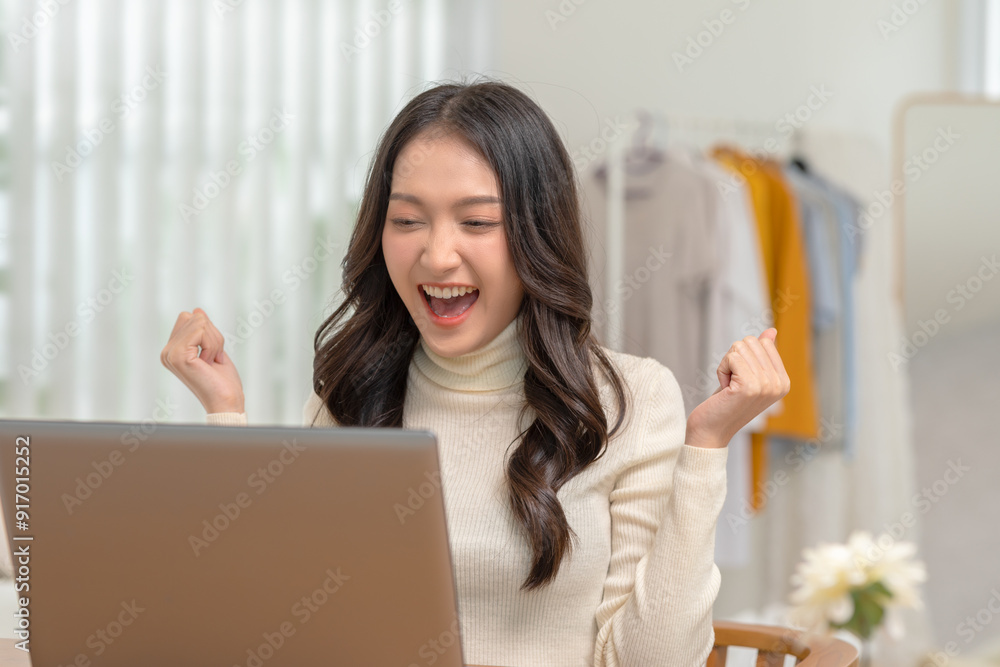 A young woman celebrates joyfully at her laptop, expressing excitement and happiness in a bright, modern workspace. A young woman celebrates joyfully at her laptop, expressing excitement and happiness in a bright, modern workspace.