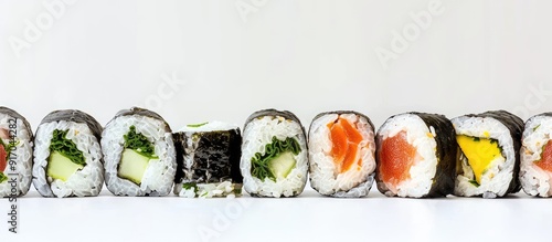 A line of maki sushi with one piece being bigger than the rest displayed in a neat arrangement on a white background with copy space image photo