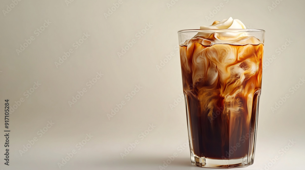 A glass of cold coffee with ice cubes and cream on top A glass of cold coffee with ice cubes and cream on top