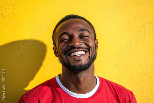 Sunlit and Smiling Black Man in Red Shirt with White T-Shirt, High-Resolution Headshot Portrait with Clean Focus and Yellow Wall Background