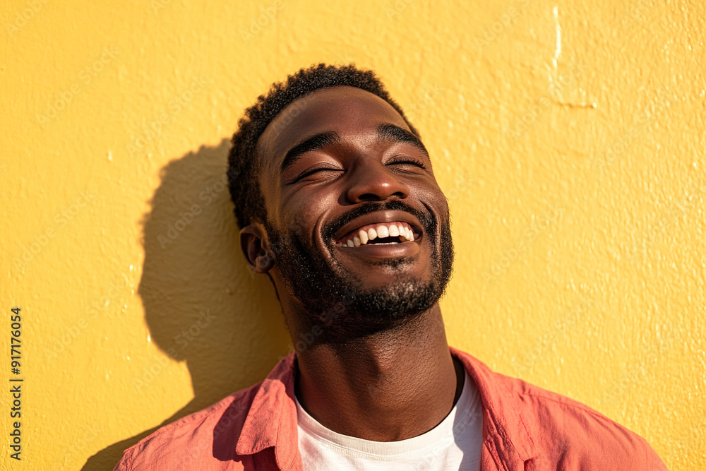 Radiant Headshot of a Black Man Smiling in a Red and White Outfit, Sunlit Face with Soft Shadows, Against a Bright Yellow Wall Radiant Headshot of a Black Man Smiling in a Red and White Outfit, Sunlit Face with Soft Shadows, Against a Bright Yellow Wall