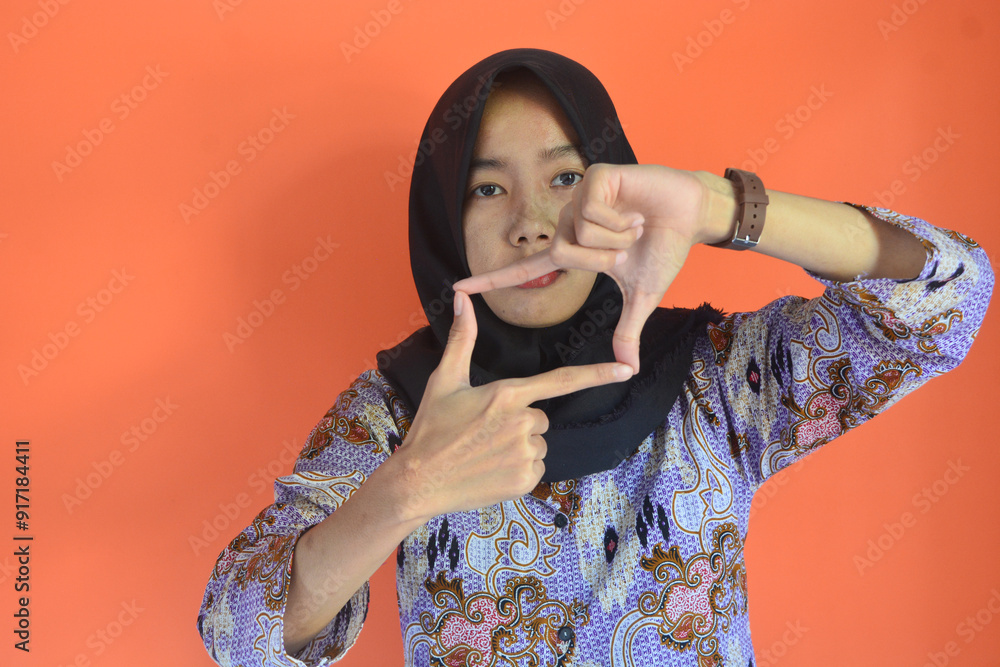Fototapeta premium Portrait of Asian Muslim woman in hijab with hand gestures above forming a photo frame