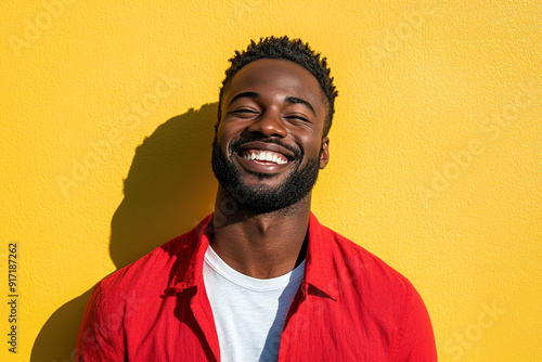 High-Quality Headshot of a Laughing Black Man, Sunlit and Smiling, Wearing a Red Shirt and White T-Shirt, Set Against a Yellow Wall