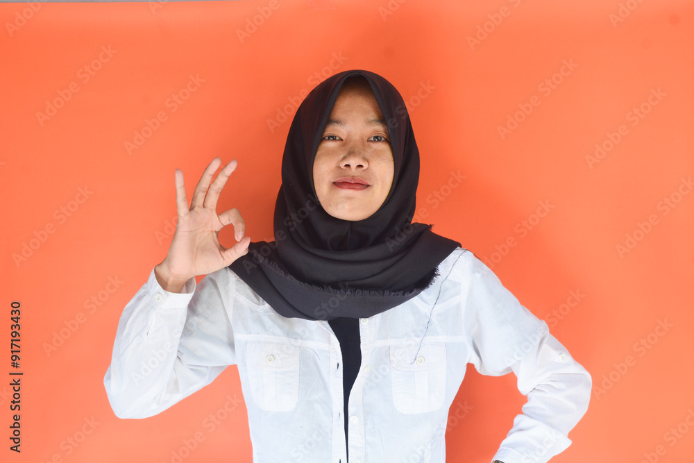 Young cheerful happy smiling pleasant successful employee business woman in her 20s wearing casual brown classic jacket showing okay okay gesture isolated on plain pastel light pink background studio Young cheerful happy smiling pleasant successful employee business woman in her 20s wearing casual brown classic jacket showing okay okay gesture isolated on plain pastel light pink background studio