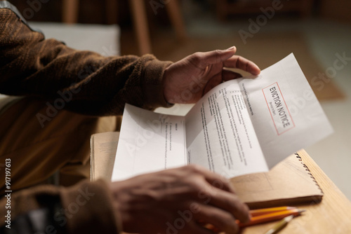 Close-up of person receiving and holding an eviction notice, focusing on their hands and the document with some text visible, creating sense of urgency and concern