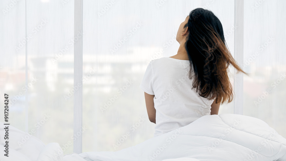 custom made wallpaper toronto digitalAsian Woman sitting on bed with her back to camera, looking out through large windows. Her hair is gently tousled, she is wrapped in white blanket, enjoying morning light in serene bedroom