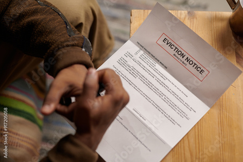 Photography Person sitting on comfortable chair and reading eviction notice placed on wooden table