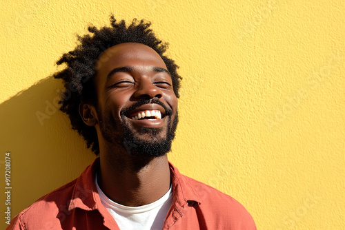 Close-Up Portrait of a Smiling Black Man in Red and White Outfit, Radiating Happiness on a Sunny Day with Yellow Wall as Backdrop