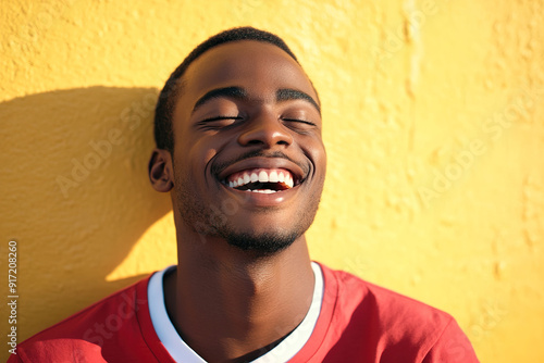 Close-Up Portrait of a Smiling Black Man in Red and White Outfit, Radiating Happiness on a Sunny Day with Yellow Wall as Backdrop