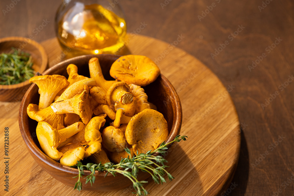 Raw chanterelles mushroom on wood scattered from a wooden wicker basket. Raw chanterelles mushroom on wood scattered from a wooden wicker basket.