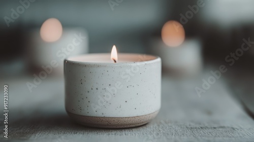 This image showcases a minimalist, white ceramic candle holder with a lit candle inside, placed on a wooden surface with a soft focus background, evoking tranquility and warmth.