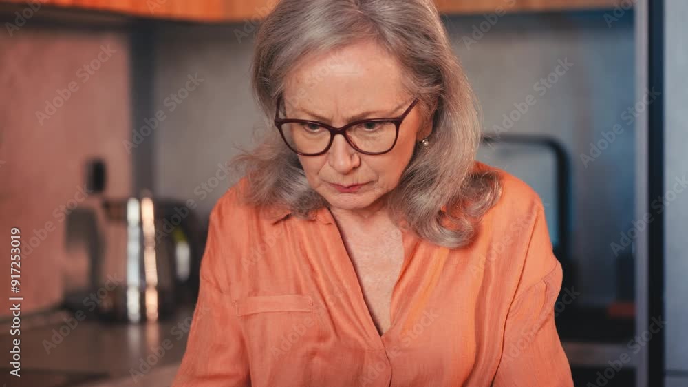 Unhappy senior woman typing on laptop, having problems with computer program Unhappy senior woman typing on laptop, having problems with computer program