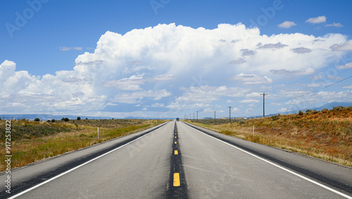 Foto Two lane road passing open high desert towards large white cloud