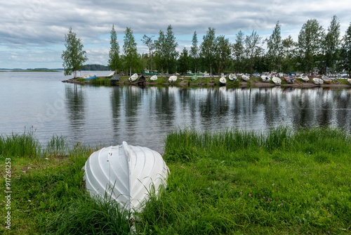 Φωτογραφία One white rowboat moored near reed grass on lake during a cloudy day