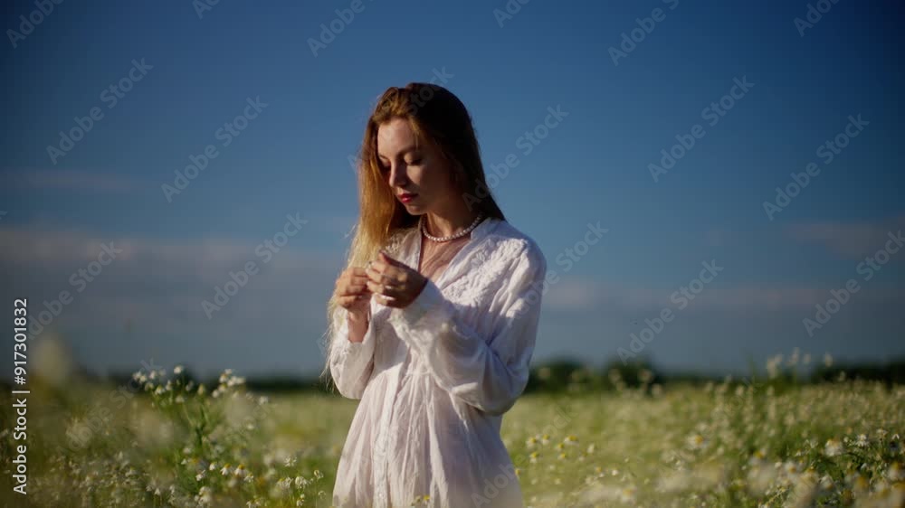 Woman in white dress gathering flowers in sunny field Woman in white dress gathering flowers in sunny field