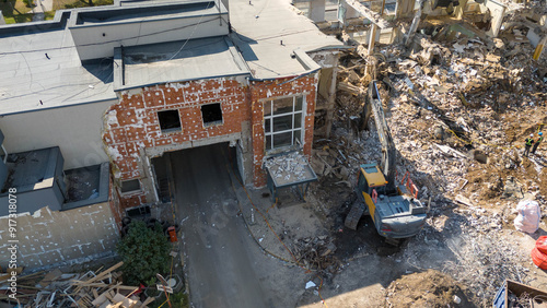 Drone photography of machinery dismantling a house and removing ruble during sunny summer day.