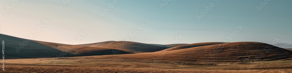 Minimalistic landscape of hilly terrain with stubble fields under a clear sky Minimalistic landscape of hilly terrain with stubble fields under a clear sky