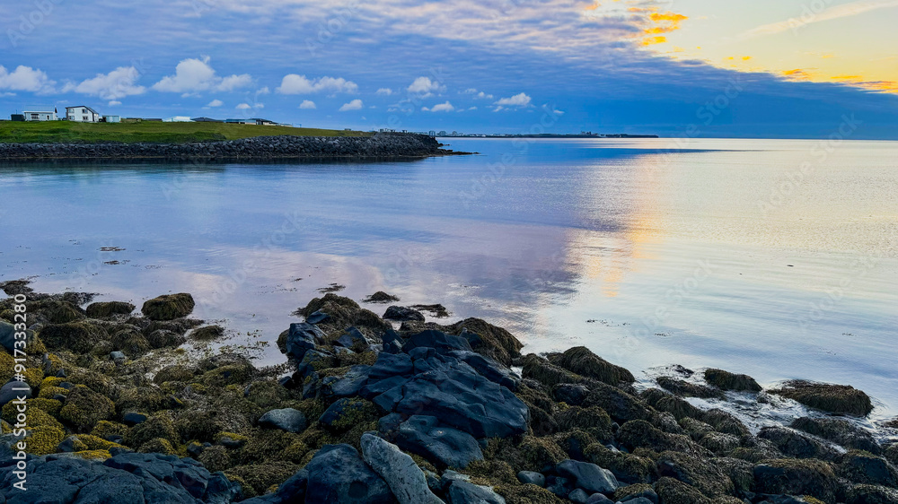 Scenic view of the Atlantic Ocean during sunset, Iceland, Keflavik. Calm ocean, low tide near the rocky shore in summer in Iceland. Scenic view of the Atlantic Ocean during sunset, Iceland, Keflavik. Calm ocean, low tide near the rocky shore in summer in Iceland.