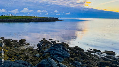 Scenic view of the Atlantic Ocean during sunset, Iceland, Keflavik. Calm ocean, low tide near the rocky shore in summer in Iceland.