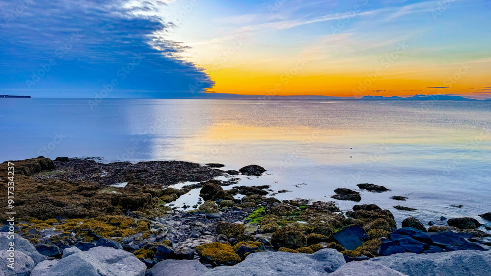 Scenic view of the Atlantic Ocean during sunset, Iceland, Keflavik. Calm ocean, low tide near the rocky shore in summer in Iceland. Scenic view of the Atlantic Ocean during sunset, Iceland, Keflavik. Calm ocean, low tide near the rocky shore in summer in Iceland.