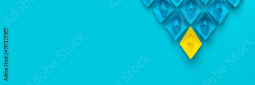Yellow paper ship ahead of blue ones leadership concept over blue background. Top view of race with yellow winning paper ship metaphor. Minimalist conceptual image of leadership