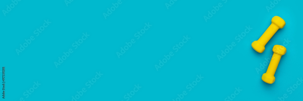 Flat lay photo of fitness dumbbells over turquoise blue background. Top view of yellow dumbbells with copy space Flat lay photo of fitness dumbbells over turquoise blue background. Top view of yellow dumbbells with copy space