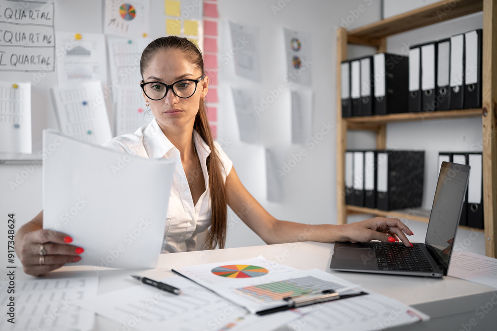 businesswoman with document and laptop in office. Woman accountant analyzing paperwork of compliance and approval before signature businesswoman with document and laptop in office. Woman accountant analyzing paperwork of compliance and approval before signature