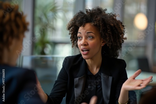 A woman engaging in a serious conversation in an office setting, her expressive hands emphasizing her point strongly.