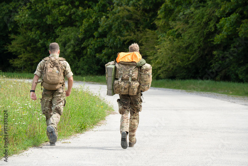 close-up of two army soldiers tabbing with 40Kg and 25Kg bergens photo